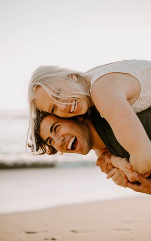 a couple on the beach playfully smiling.
